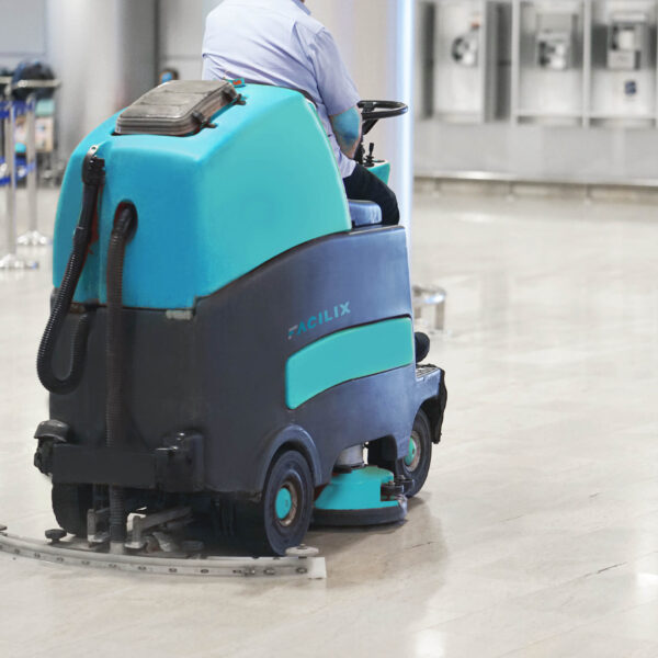 Man driving professional floor cleaning machine at airport or railway station or supermarket. Floor care and cleaning service